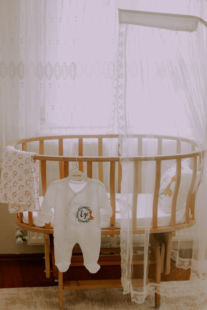 hero-img-02 A serene baby room featuring a wooden crib and a cute baby outfit.